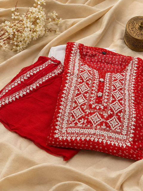 Beautiful bright red flared Bandhani Print kurta set featuring elegant white detailing, matching straight pants, and a coordinated dupatta. Slight variation in color & design may occur