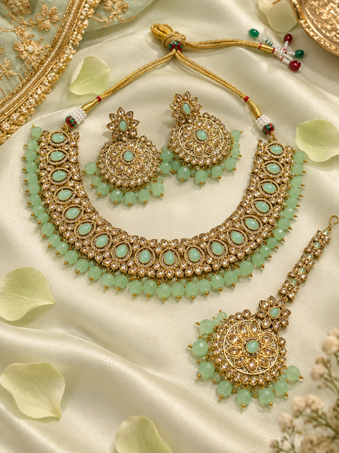 Elegant polki Necklace Set featuring beautiful Kundan stones, pearl detailing and bead drops. Comes with matching earrings and maang tikka. Slight variation in colour and design may be possible.