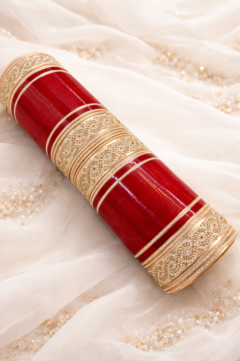 A stunning red bridal chura set featuring rich glossy bangles paired with intricately designed gold-toned kadas. Embellished with fine stone detailing and delicate patterns, this set perfectly blends traditional elegance with a modern touch—ideal for wedd