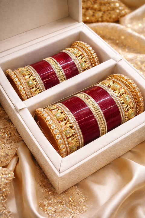 This bridal bangle set features intricate elephant motifs, symbolizing tradition and royal elegance, combined with fine gold detailing, colorful stone accents, and a rich red base—creating a majestic and culturally inspired bridal look.