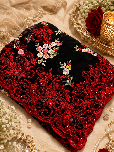 Exquisite black net saree featuring intricate floral embroidery, shimmering stone embellishments, and a richly detailed designer border for a luxurious statement look. Attached blouse fabric is included,the blouse worn by the model is for reference