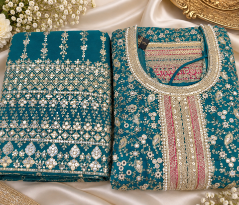 Elegant Chanderi Silk suit featuring all-over heavy embroidery and mirror work with a beautifully detailed neckline. Paired with a heavily embroidered palazzo and a gorgeous matching dupatta for a rich festive look. Slight variation in colour & design