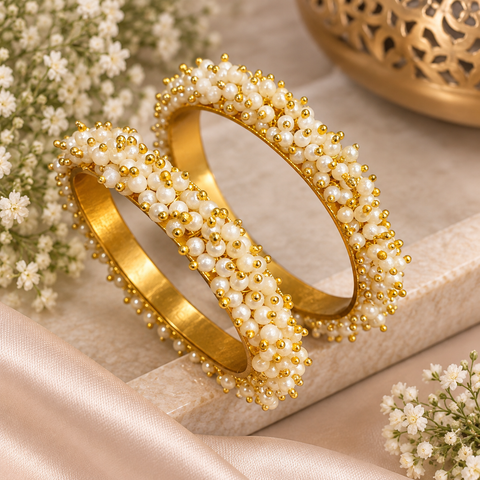 Pearl Cluster Bangles: Gold-tone bangles adorned with delicate white pearl clusters and tiny golden beads. A lovely choice for festive and wedding outfits. Set includes 2 bangles; price is per set.(Slight variations in color & design is possible)