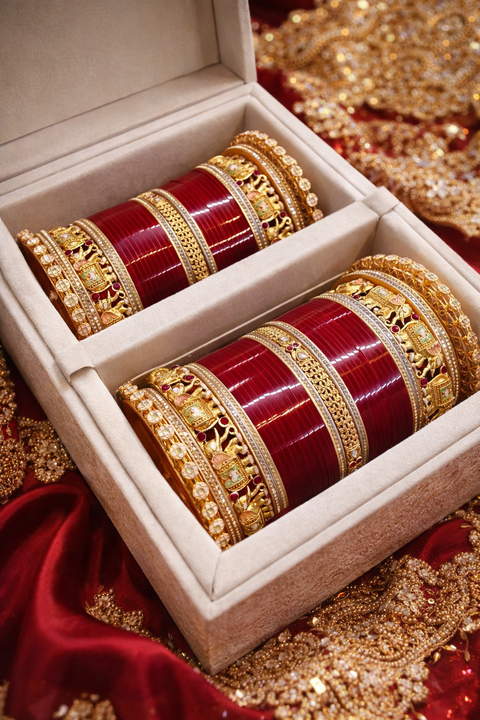 This bridal bangle set features intricate elephant motifs, symbolizing tradition and royal elegance, combined with fine gold detailing, colorful stone accents, and a rich red base—creating a majestic and culturally inspired bridal look.