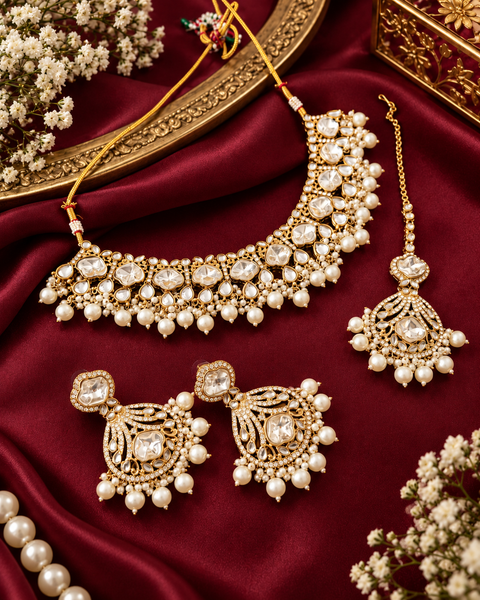 Elegant Kundan Necklace Set featuring beautiful Kundan stones, pearl detailing and bead drops. Comes with matching earrings and maang tikka. Slight variation in colour and design may be possible.