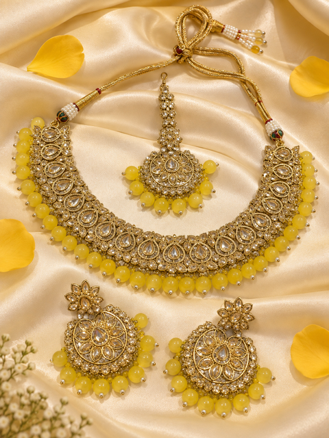 Elegant polki Necklace Set featuring beautiful Kundan stones, pearl detailing and bead drops. Comes with matching earrings and maang tikka. Slight variation in colour and design may be possible.