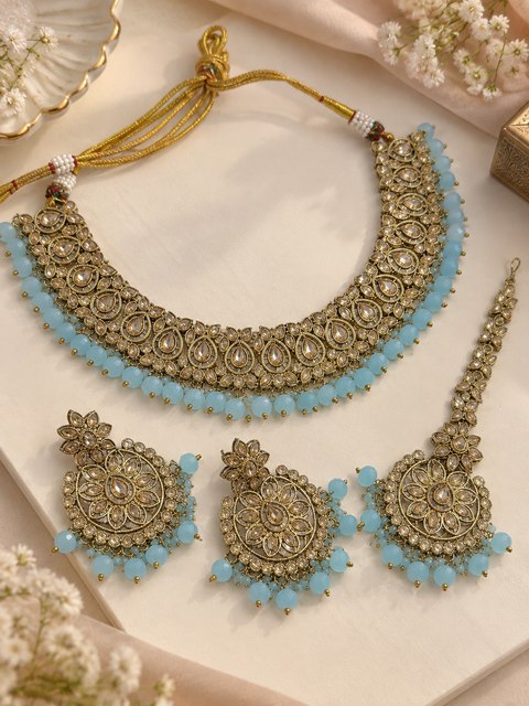 Elegant polki Necklace Set featuring beautiful Kundan stones, pearl detailing and bead drops. Comes with matching earrings and maang tikka. Slight variation in colour and design may be possible.