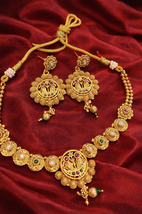 Elegant matte-finish light gold necklace set featuring intricate traditional motifs with subtle multicolor stone detailing, paired with matching statement earrings. Perfect for adding a graceful, timeless charm to any ethnic look. ✨