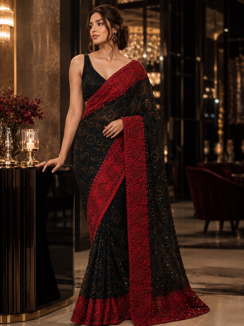 Elegant black net saree with all-over black stone work and a striking red embroidered border with red stones, crafted for luxurious & unforgettable party look,Blouse Piece is For Reference Only, Blouse Piece Attached to Saree(slight variation is possible)