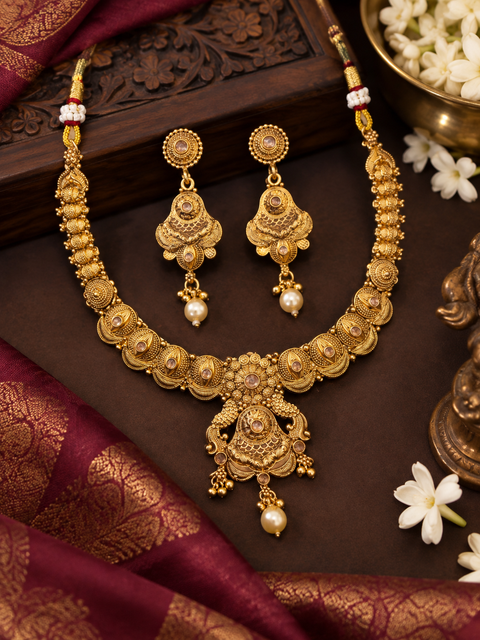 Elegant matte gold-finish Temple Jewellery Set with beautifully detailed peacock designs and stone accents. Comes with matching jhumka earrings(slight variation in color & design may occur)