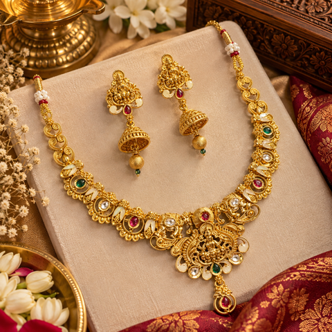 Elegant matte gold-finish Temple Jewellery Set Goddess Lakshmi  motif with beautifully detailed elephant designs and green ,Ruby stone accents. Comes with matching jhumka earrings(slight variation in color & design may occur)