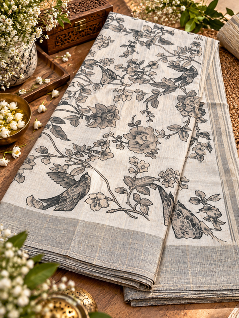 Ivory Chanderi Silk Saree with floral & bird patterns and a subtle zari border. Lightweight and elegant. Model blouse for reference only; blouse piece attached. Slight variation possible.