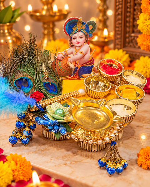 Beautiful handcrafted Krishna Puja Décor Set with peacock feather detailing, golden accents and decorative bowls. Comes with kumkum, rice, chandan and mishri—perfect for puja, festive décor and gifting. Slight variation in colour or design is possible.