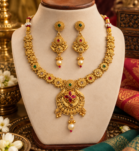 Elegant South Indian temple-style necklace set with intricate floral detailing, red and green stones, and pearl drops. Comes with matching earrings.(slight variation in color & design may occur)
