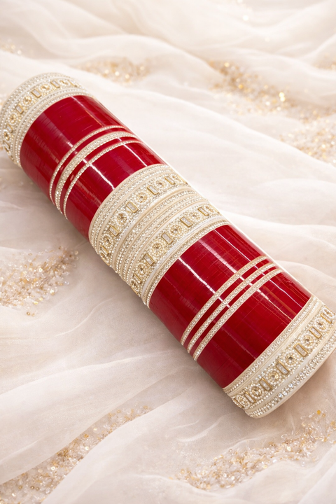 A stunning Cherry bridal chura set featuring rich glossy bangles paired with intricately designed silver-toned kadas. Embellished with fine stone detailing and delicate patterns, this set perfectly blends traditional elegance with a modern touch