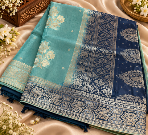 Dola Silk Saree with elegant all-over floral zari weaving and a rich contrasting woven border with detailed pallu. Soft, graceful drape with a luxurious festive look. Contrast blouse piece included.Slight variation in colour and design is possible.