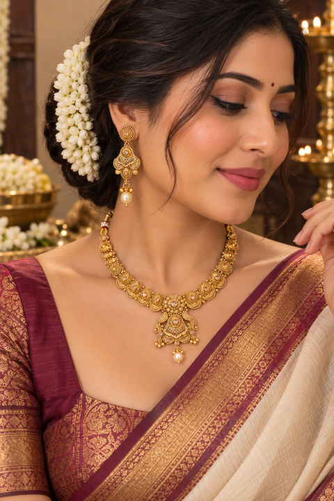 Elegant matte gold-finish Temple Jewellery Set with beautifully detailed peacock designs and stone accents. Comes with matching jhumka earrings(slight variation in color & design may occur)