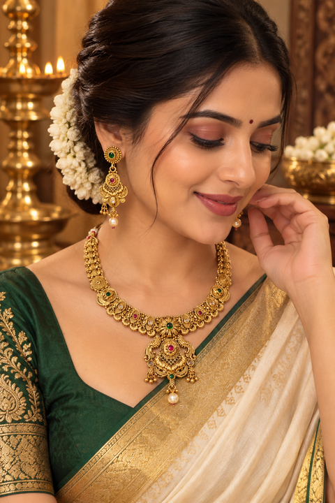 Elegant matte gold-finish Temple Jewellery Set with beautifully detailed peacock designs and stone accents. Comes with matching jhumka earrings(slight variation in color & design may occur)
