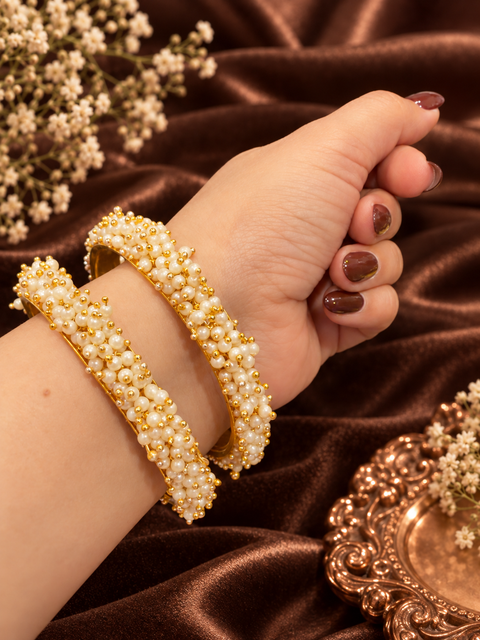 Pearl Cluster Bangles: Gold-tone bangles adorned with delicate white pearl clusters and tiny golden beads. A lovely choice for festive and wedding outfits. Set includes 2 bangles; price is per set.(Slight variations in color & design is possible)