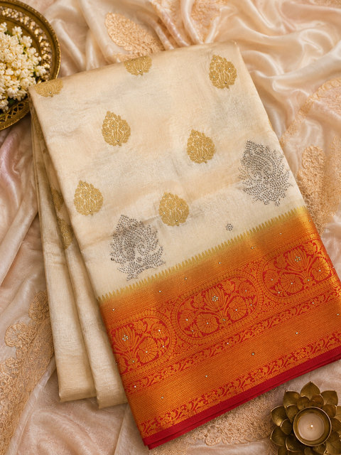 Elegant Off-White Banarasi Silk Saree adorned with delicate zari-woven butis, a rich contrast red-gold pallu and graceful tassel detailin,Comes with an unstitched running blouse piece attached to the saree (slight variation in color and design is possible