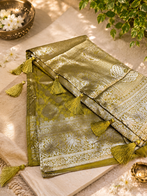 Elegant Olive Green Banarasi Silk Saree featuring rich zari weaving, intricate traditional motifs and graceful tassel detailing on pallu,Comes with an unstitched running blouse piece attached to the saree (slight variation in color and design is possible